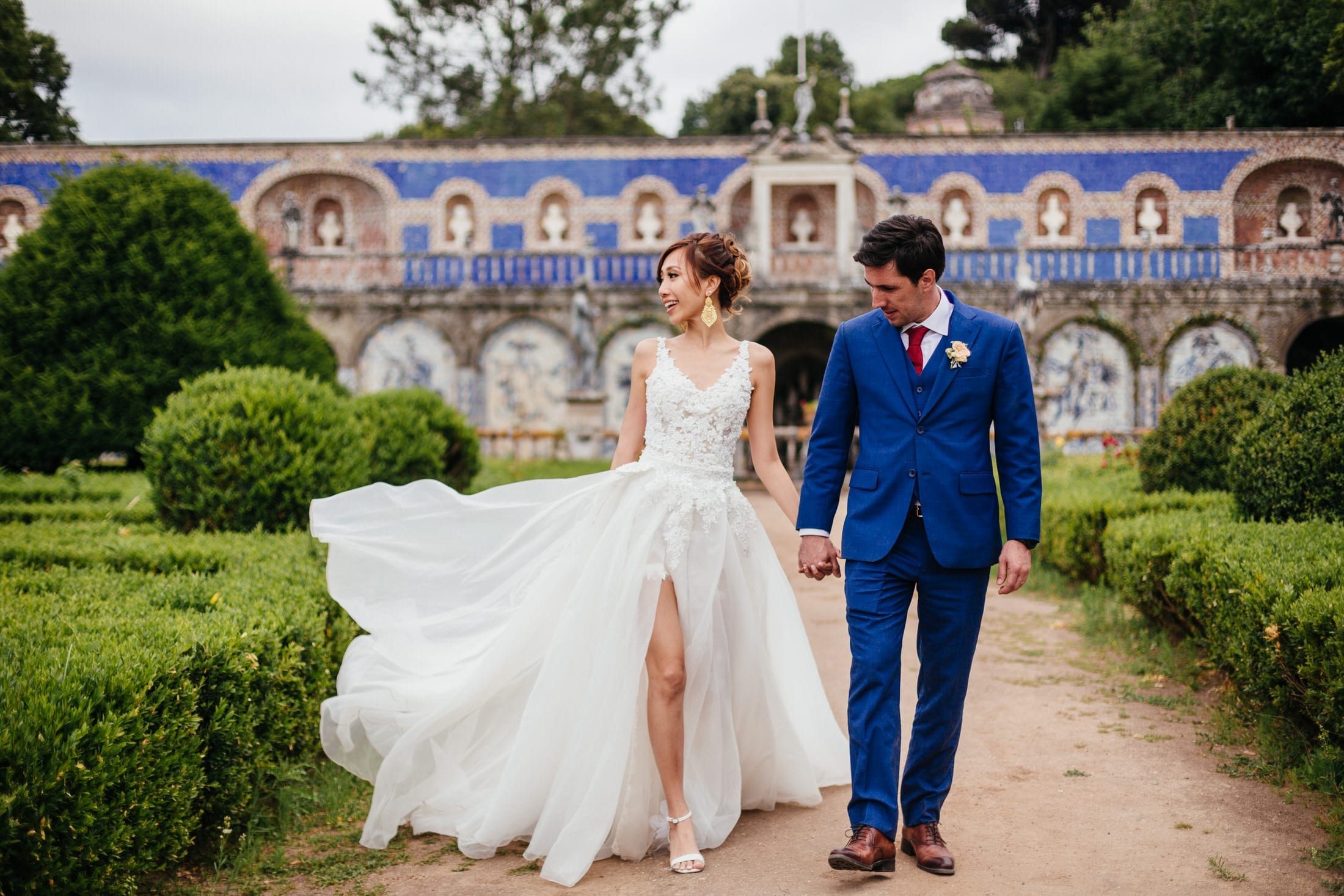 the bride and the groom walk hand in hand in the fronteira palace garden on their wedding day. Photo by Lisbon Wedding Photographer Your Story in Photos