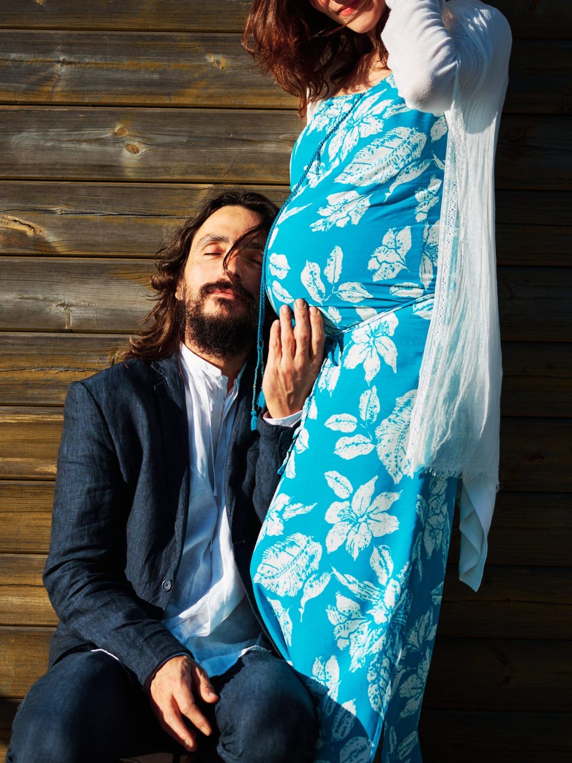 a man rests his head on his partner's pregnant belly during a maternity shoot in Portugal