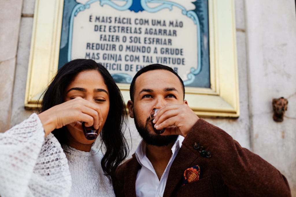 a couple drinks ginjinha in Lisbon during their engagement session