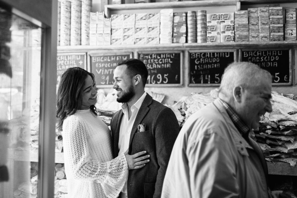 a couple hugs inside a codfish shop during their engagment session in Lisbon, Portugal