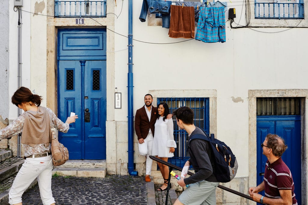 Passers-by interact with a couple during their engagement photo shoot in Lisbon