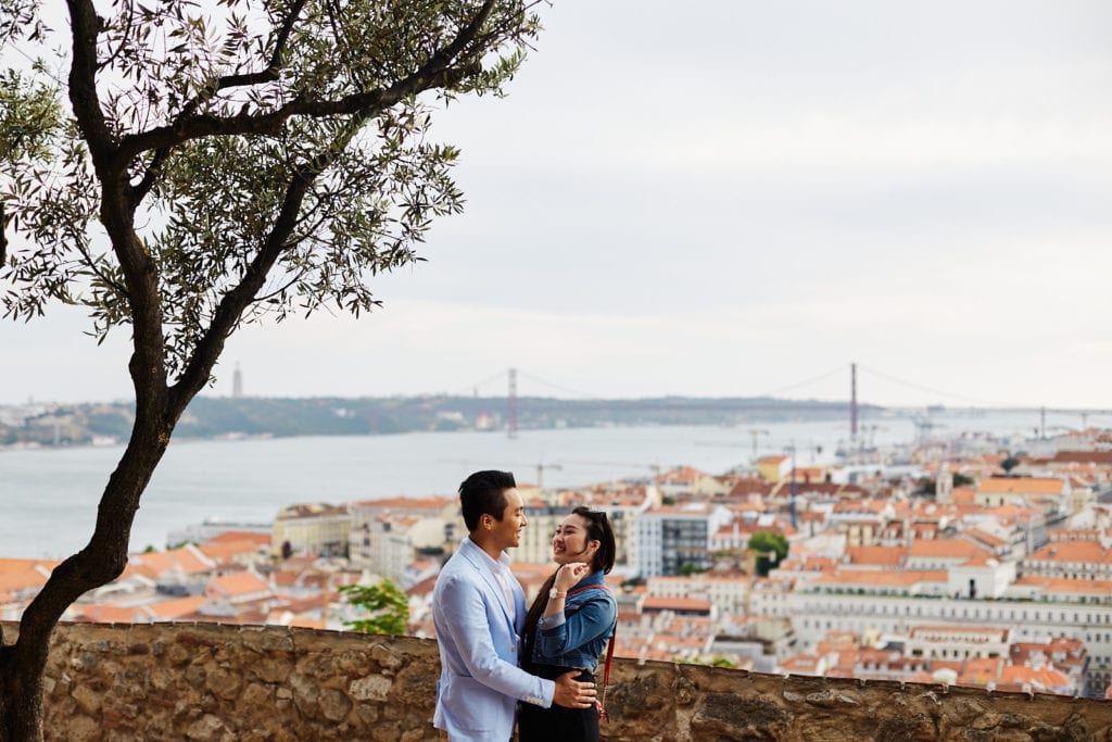 a couple hugs at Lisbon Castle with Lisbon city as a backdrop, after an emotional marriage proposal