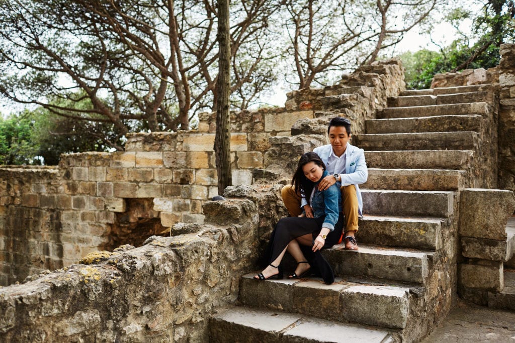 A couple sit on a stairway in Lisbon's Castle for a romantic shoot after an emotional marriage proposal