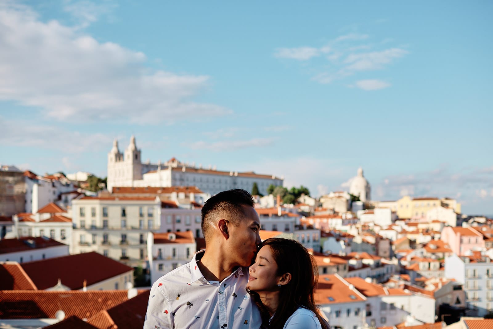 Eliza Sam and Joshua Ngo in a romantic pose with Alfama's roofs as a backdrop, during a photoshoot in Lisbon
