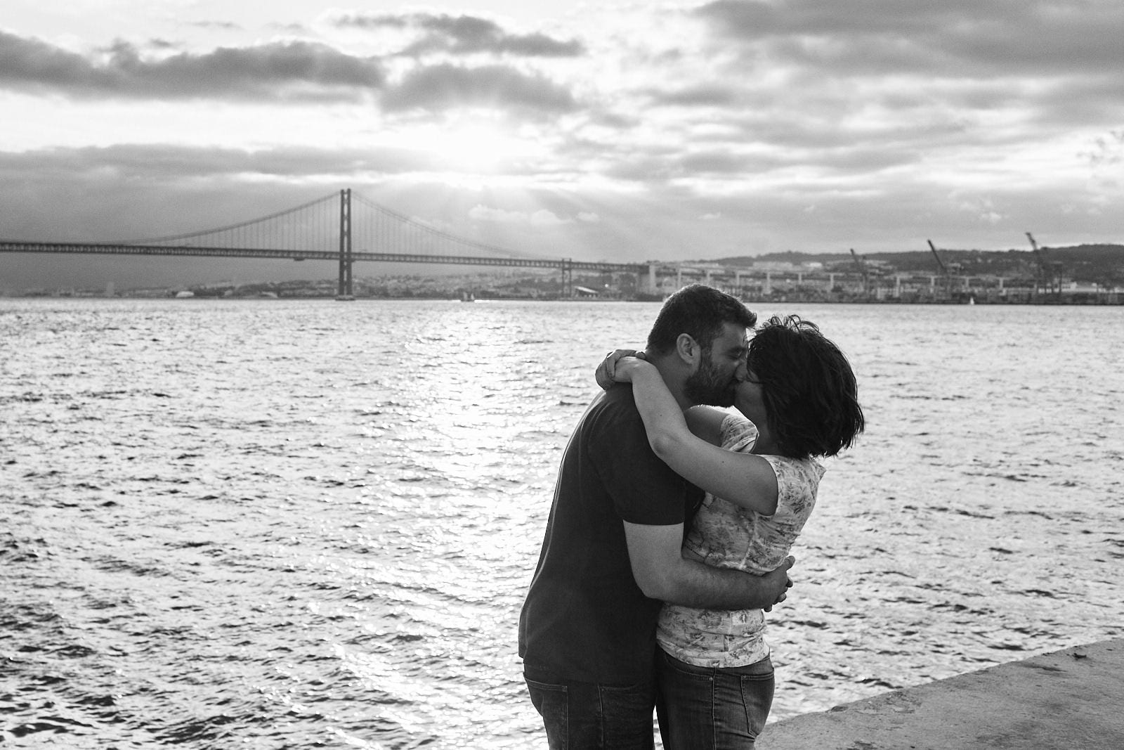 Lisbon Photographers Emanuele and Romana from Your Story in Photos in a romantic pose captured by one of their clients on the south bank of the Tejo river in Lisbon