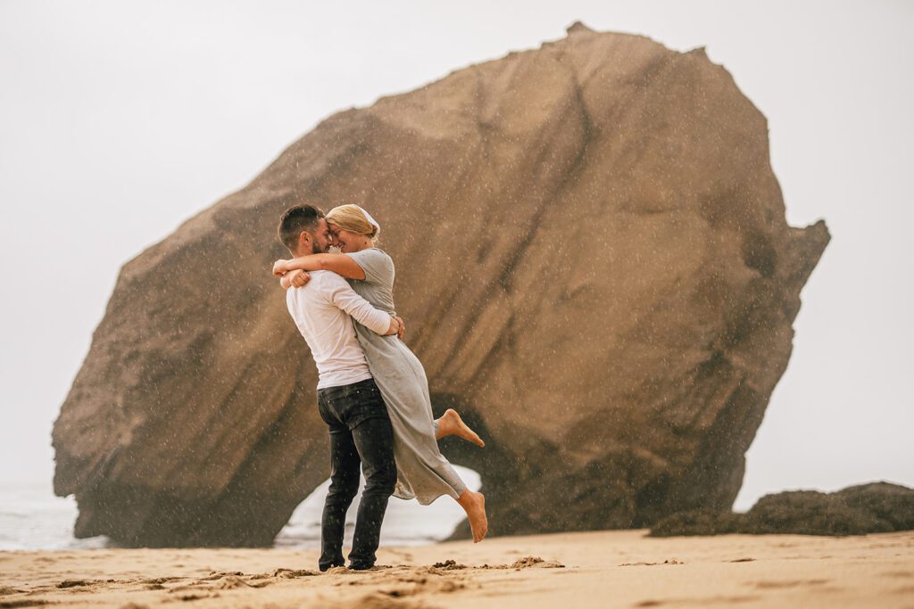 couple hugging in rain on the beach in Santa Cruz, Lisbon, Portugal