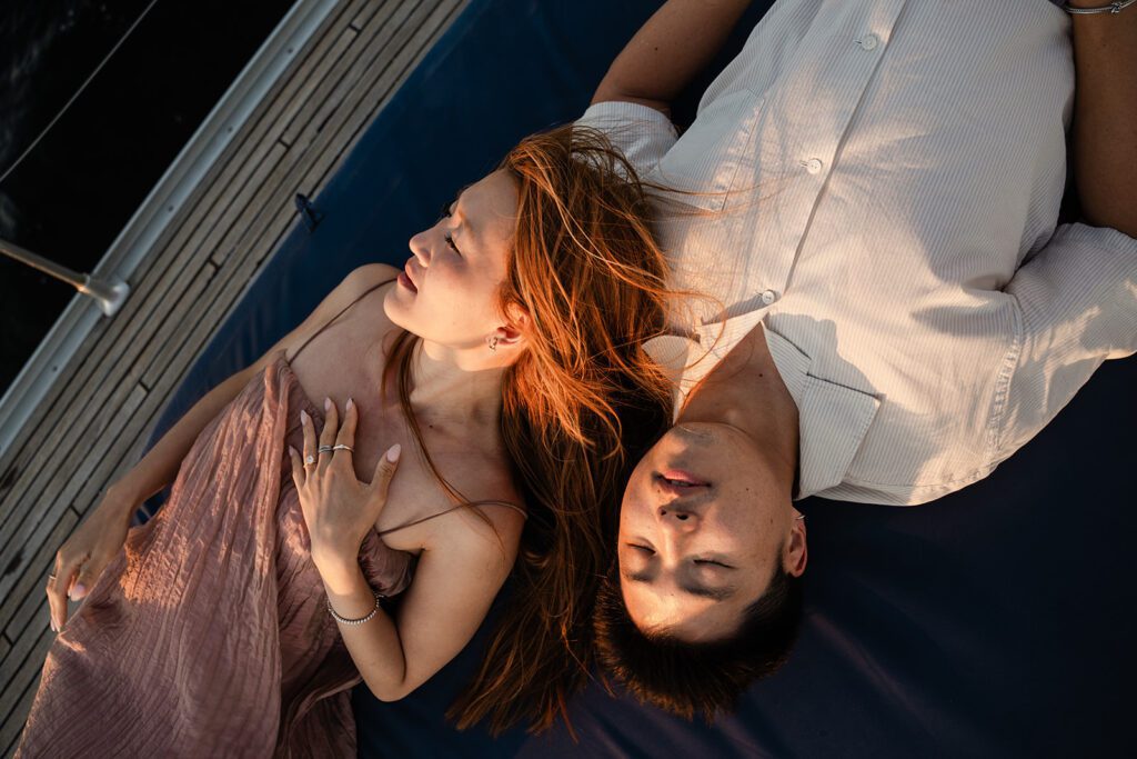 a couple lying on a boat deck in lisbon's tagus river in golden light during an engagement photoshoot