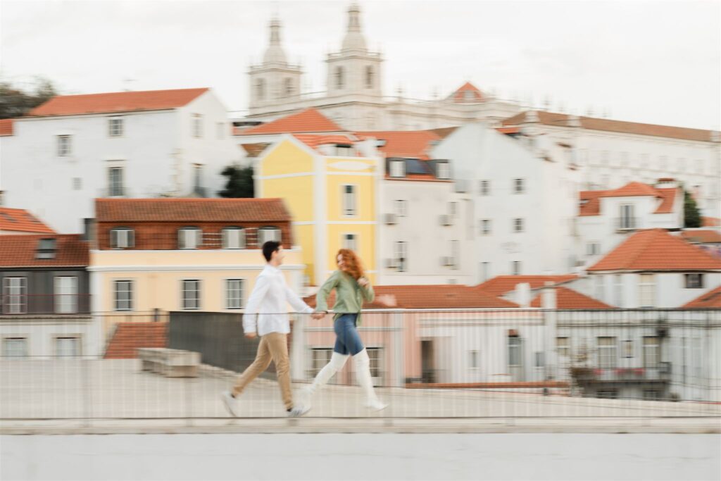 Panning shot of a couple running in a viewpoint in Lisbon
