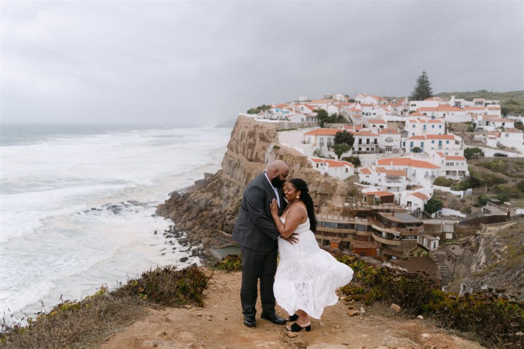 An engaged couple hugs on the cliffs of Azenhas do Mar in Portugal
