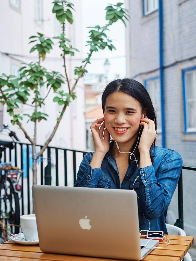 a girl sitting outdoor at café in Lisbon with her laptop as part of a personal branding session with Lisbon photographer Your Story in Photos