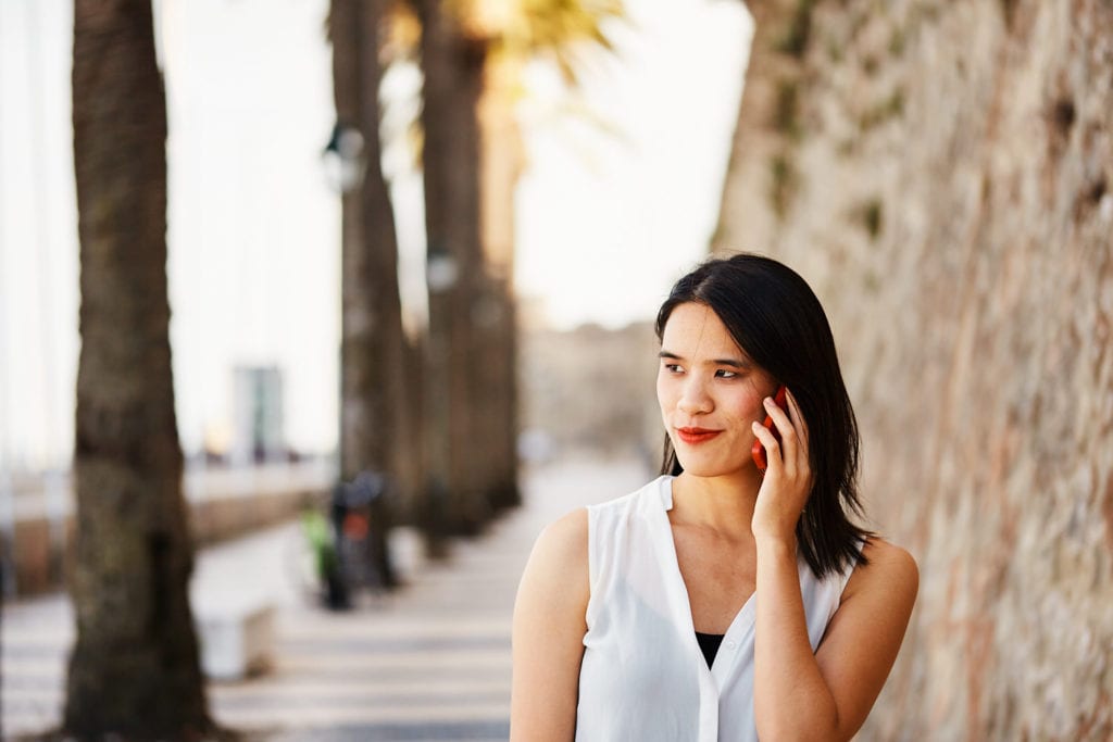 a girl walks in Cascais waterfront, while speaking on her phone, as part of a professional photoshoot for branding purposes