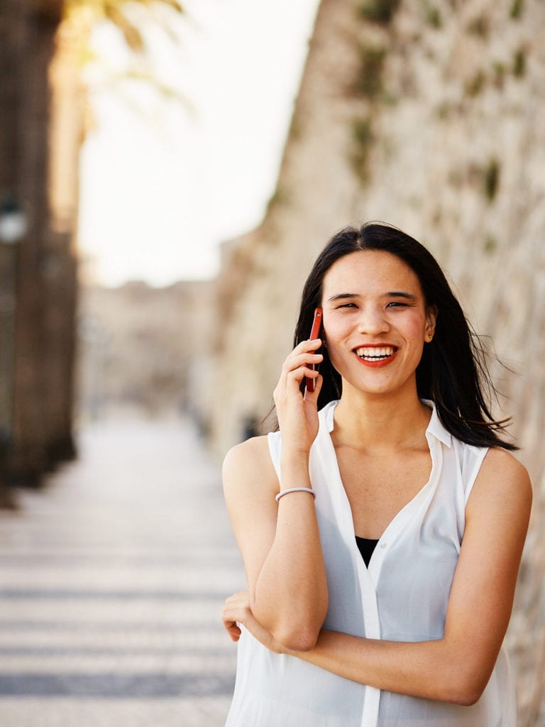 a girl smiles at the camera while speaking on the phone as part of her professional branding photo session in Cascais, Lisbon