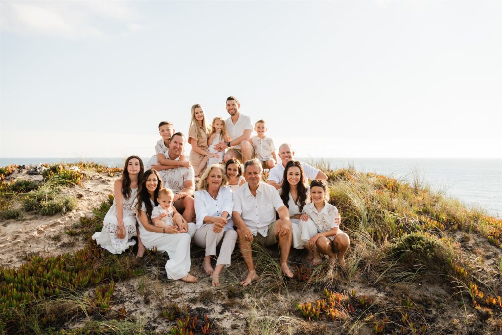 an extended family posing for a photo on the beach in Portugal